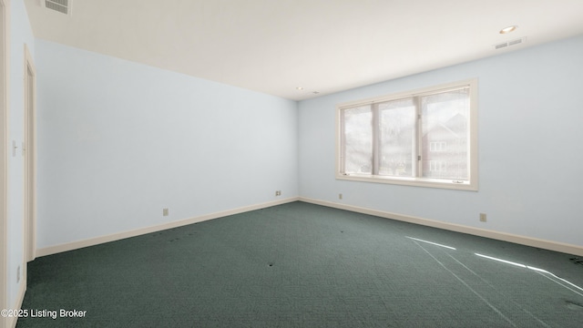 unfurnished room featuring dark colored carpet, visible vents, and baseboards