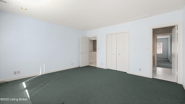 unfurnished bedroom with baseboards, visible vents, dark colored carpet, and a closet