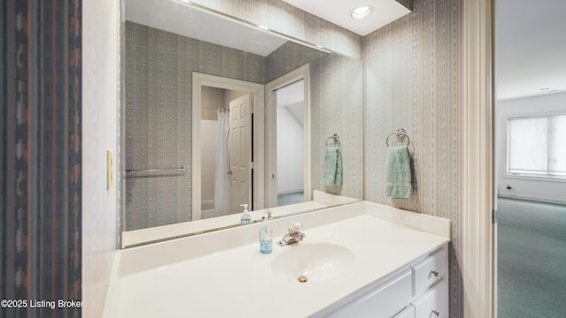 bathroom featuring vanity and wallpapered walls