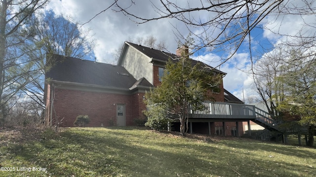 view of home's exterior with brick siding, a lawn, a wooden deck, and stairway