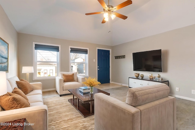 living room with vaulted ceiling, light carpet, ceiling fan, and baseboards