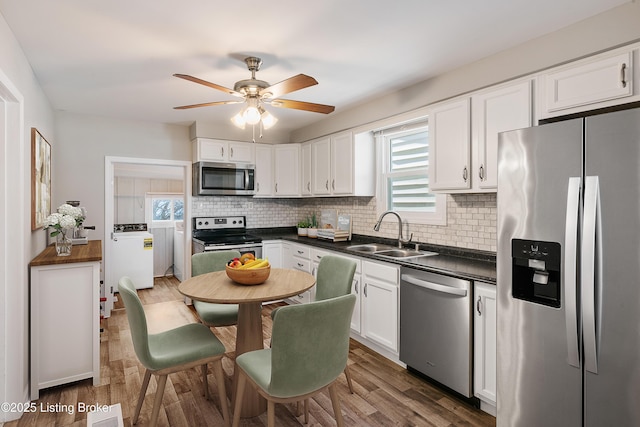 kitchen with separate washer and dryer, a sink, white cabinetry, appliances with stainless steel finishes, and dark countertops