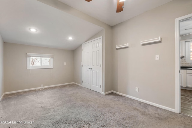 unfurnished bedroom with ceiling fan, lofted ceiling, carpet flooring, baseboards, and a closet