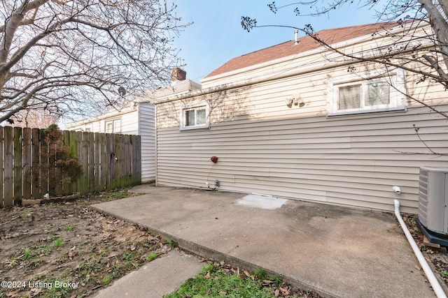 back of property with a patio, a chimney, central AC unit, and fence