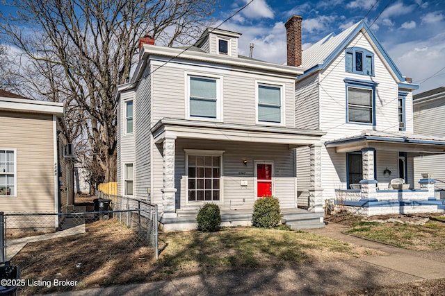 view of front of property with covered porch, fence, and a chimney