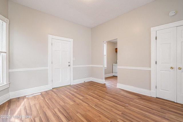 unfurnished room with light wood finished floors, visible vents, and baseboards