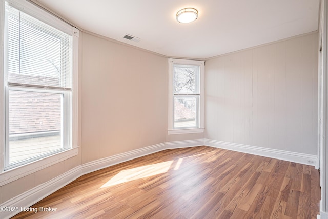 empty room featuring wood finished floors, visible vents, and baseboards