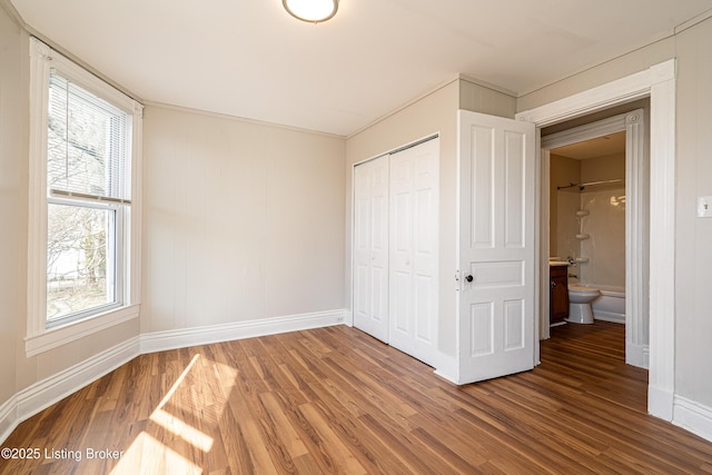 unfurnished bedroom with a closet, baseboards, and wood finished floors