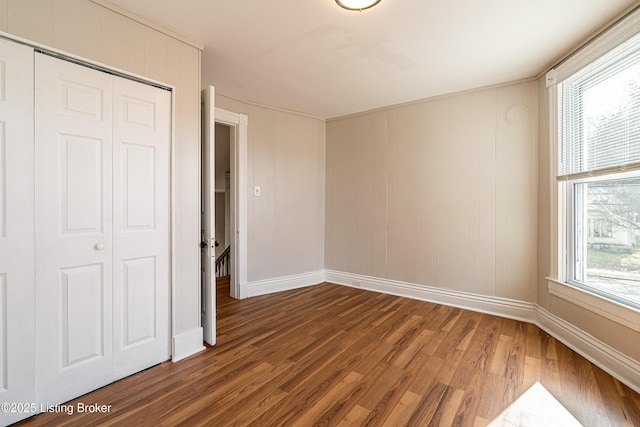 unfurnished bedroom featuring a closet, baseboards, and wood finished floors