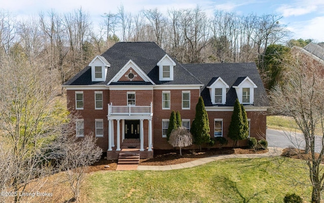 view of front of house featuring a balcony, a front lawn, and brick siding