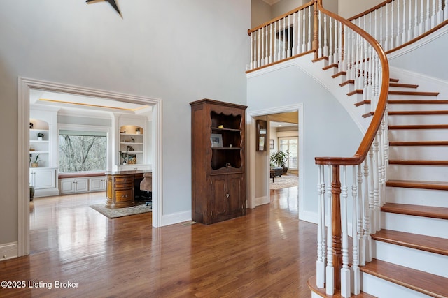 foyer featuring stairway, a high ceiling, baseboards, and wood finished floors