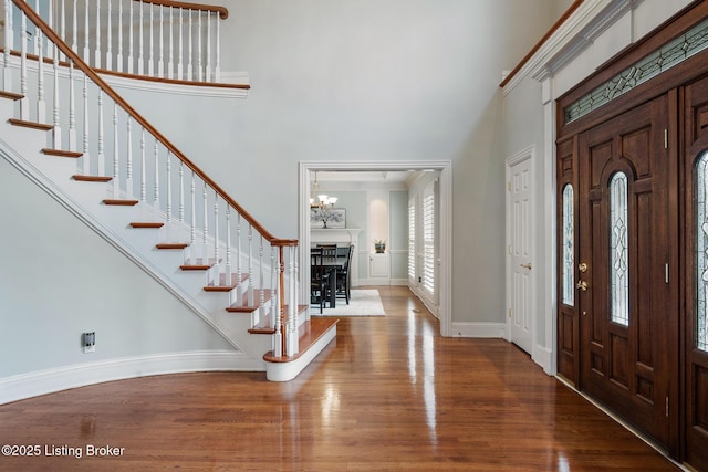 entrance foyer featuring stairs, wood finished floors, a towering ceiling, and baseboards