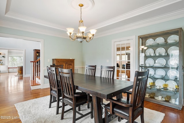 dining room featuring an inviting chandelier, stairs, ornamental molding, and wood finished floors