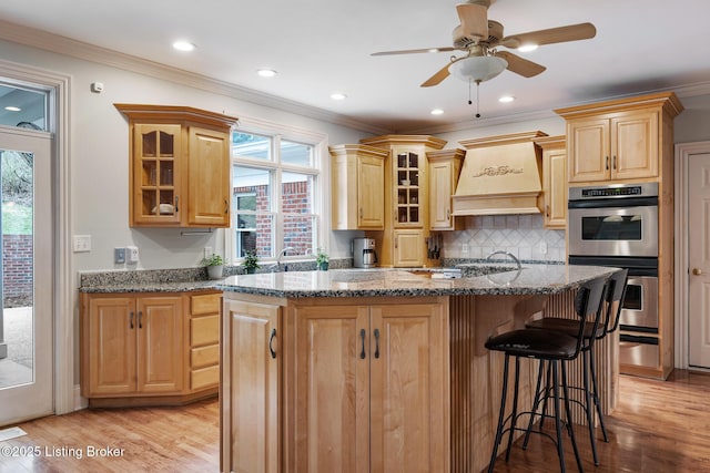 kitchen featuring a center island, light wood finished floors, stainless steel appliances, backsplash, and a kitchen bar