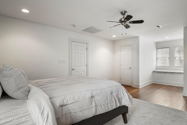 bedroom with baseboards, wood finished floors, visible vents, and recessed lighting