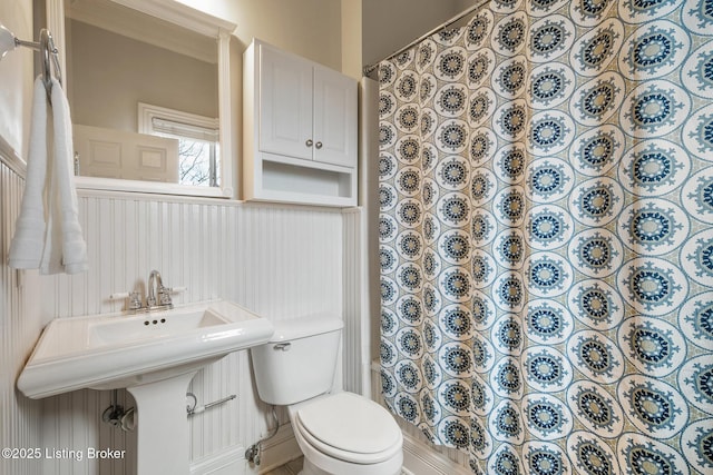 bathroom with ornamental molding, toilet, and a shower with curtain