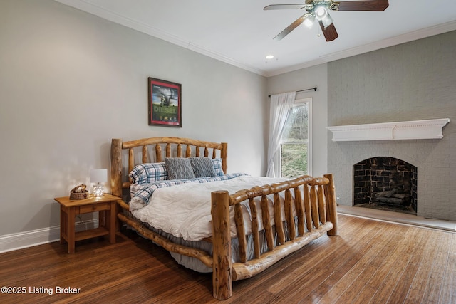 bedroom featuring crown molding, a fireplace, baseboards, and wood finished floors