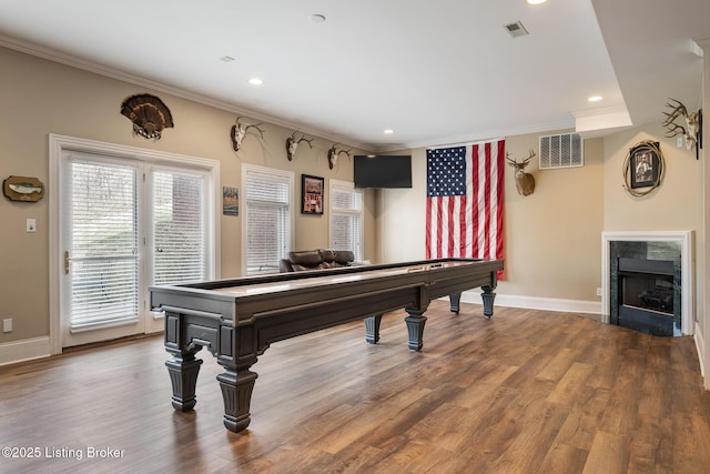 playroom with a premium fireplace, visible vents, crown molding, and wood finished floors