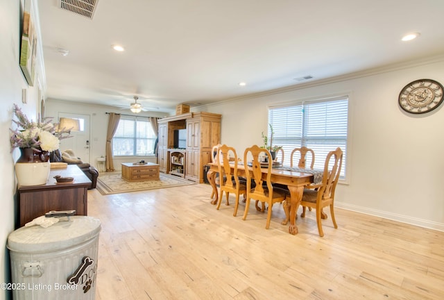 dining room with visible vents, light wood-style flooring, crown molding, and baseboards