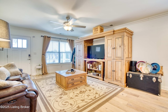 living area featuring crown molding, a ceiling fan, light wood-type flooring, and baseboards