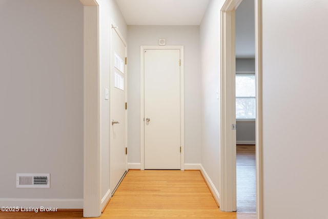 hallway featuring light wood-style flooring, visible vents, and baseboards