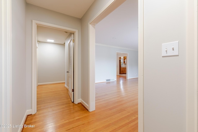 hallway with light wood-style floors, visible vents, and baseboards