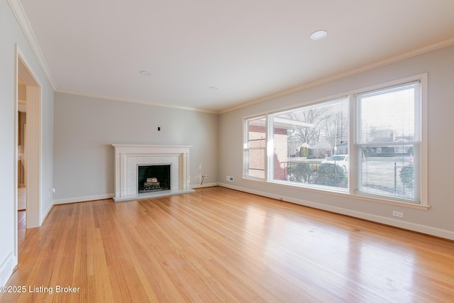 unfurnished living room featuring ornamental molding, light wood-type flooring, a fireplace with raised hearth, and baseboards