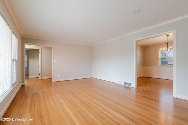 spare room featuring a notable chandelier, visible vents, baseboards, light wood-style floors, and crown molding