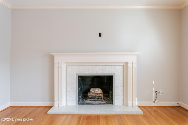 room details featuring ornamental molding, a tile fireplace, wood finished floors, and baseboards