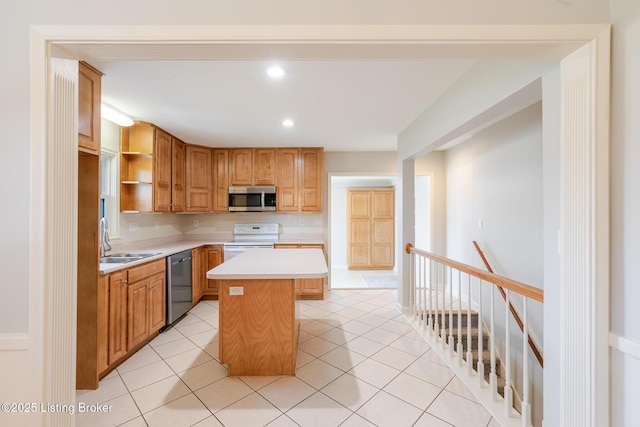 kitchen with appliances with stainless steel finishes, light countertops, a sink, and light tile patterned floors