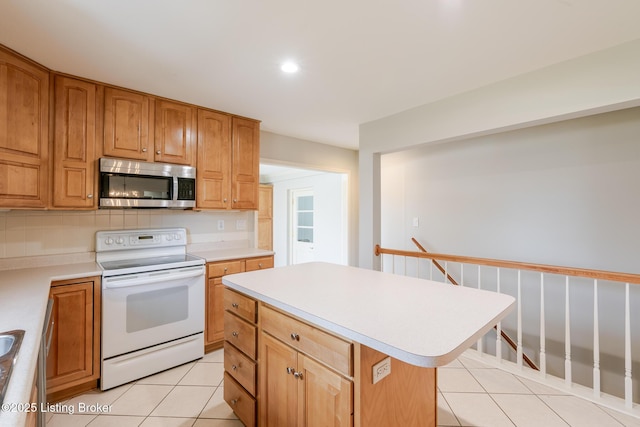 kitchen with light tile patterned floors, electric stove, stainless steel microwave, light countertops, and backsplash