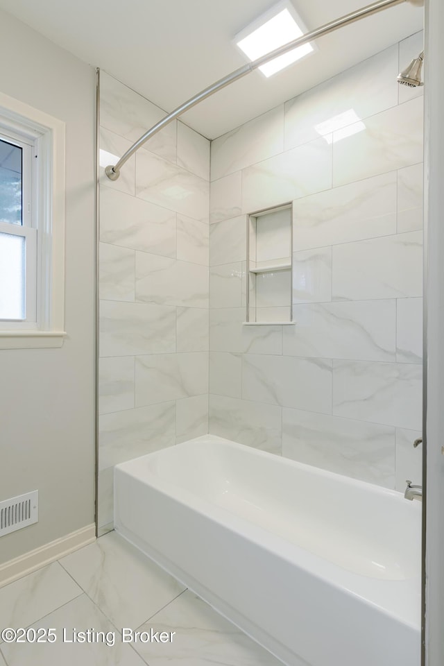 bathroom with marble finish floor, tub / shower combination, visible vents, and baseboards