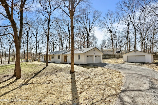 single story home with a garage, metal roof, an outbuilding, and fence