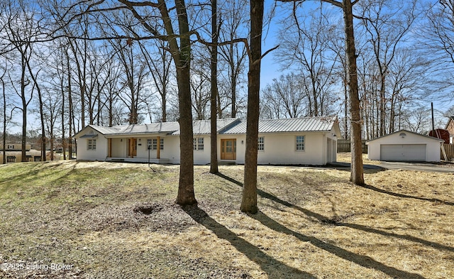 ranch-style home with a garage, an outbuilding, metal roof, and stucco siding