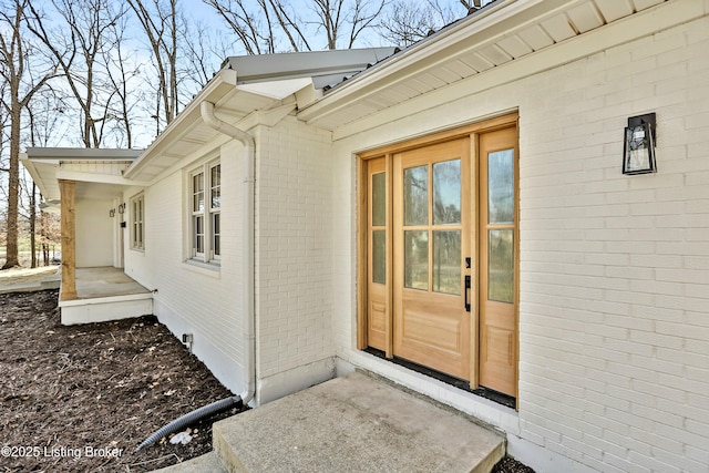 doorway to property with brick siding