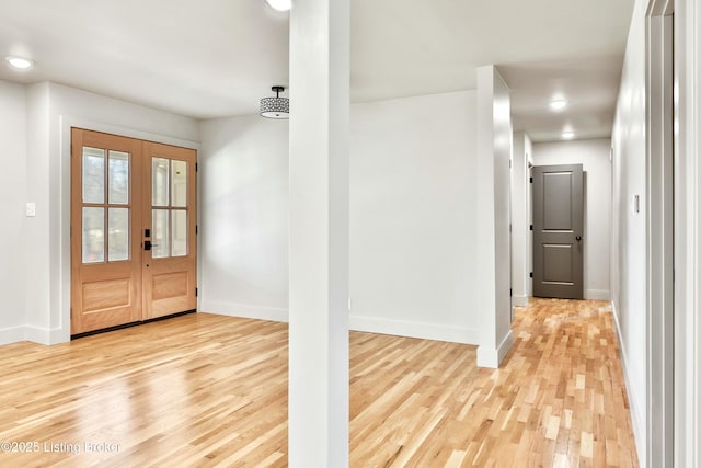 foyer entrance with light wood finished floors, baseboards, and french doors