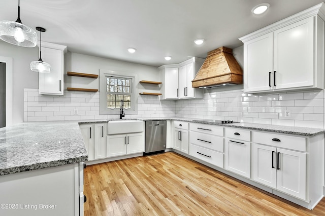 kitchen featuring custom range hood, stainless steel dishwasher, white cabinetry, open shelves, and a sink