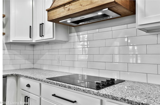 kitchen with range hood, black electric stovetop, white cabinets, and decorative backsplash