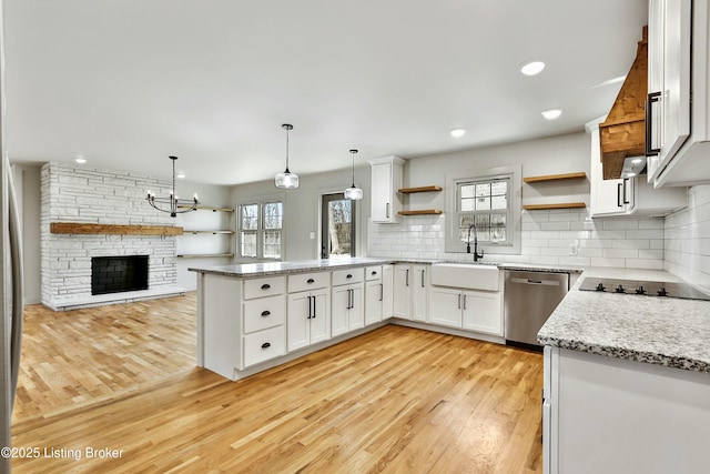 kitchen featuring dishwasher, a peninsula, black electric cooktop, open shelves, and a sink