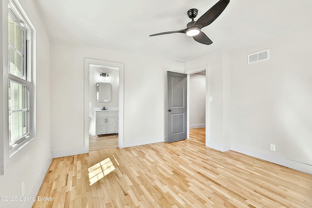 unfurnished bedroom with visible vents, a sink, ensuite bath, wood finished floors, and baseboards