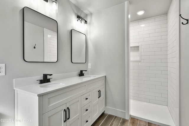 bathroom featuring wood finish floors, a sink, baseboards, and double vanity