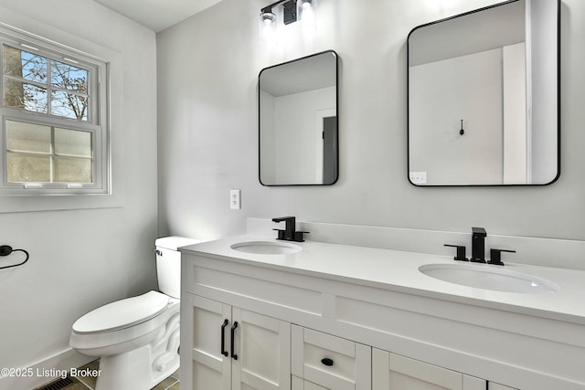 bathroom with a sink, toilet, and double vanity