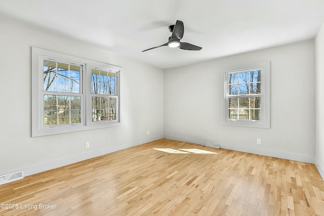 empty room featuring wood finished floors, visible vents, and a ceiling fan