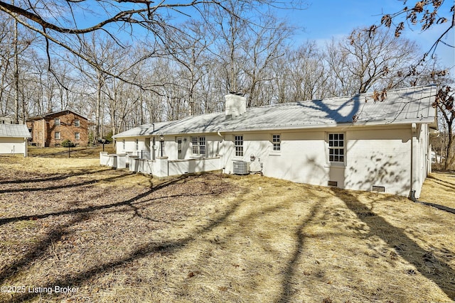 rear view of house with brick siding, a chimney, and central air condition unit