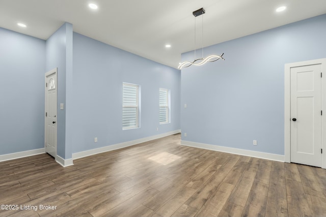 unfurnished dining area featuring baseboards, wood finished floors, and recessed lighting