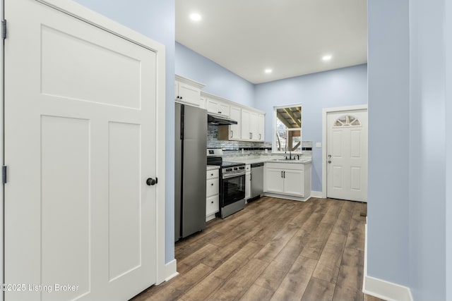 kitchen featuring stainless steel appliances, a sink, white cabinetry, and decorative backsplash