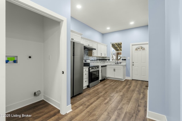 kitchen featuring under cabinet range hood, dark wood-type flooring, a sink, white cabinets, and appliances with stainless steel finishes