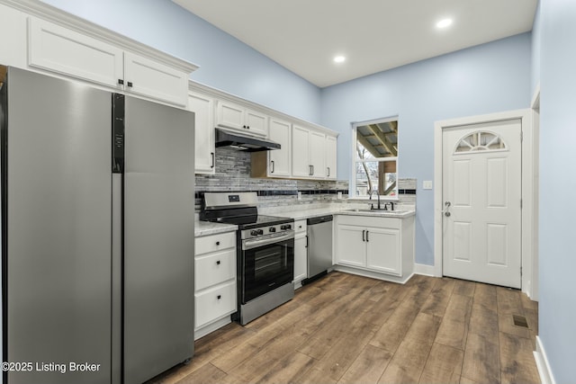 kitchen with stainless steel appliances, a sink, white cabinetry, and under cabinet range hood