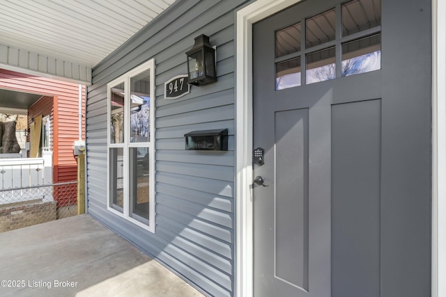 property entrance featuring covered porch and fence