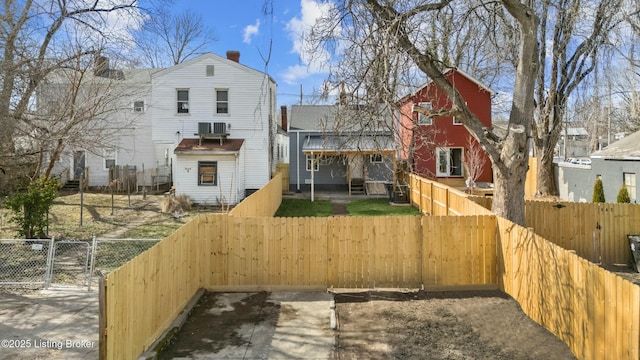 rear view of property with cooling unit, a gate, and a fenced backyard